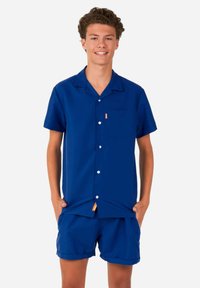 Blauwe T-shirt met korte mouwen, een zak, knoopsluiting en oranje accent. Gecombineerd met bijpassende blauwe shorts, beide gemaakt van een glad materiaal.