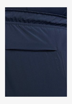 Tecido DRI-FIT azul-marinho com uma textura suave, apresentando um bolso horizontal e uma marcação subtil. Design simples com elementos funcionais.