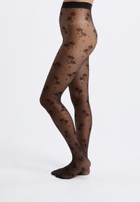 Tights negras con un patrón que presenta diseños florales y lunares. Hechas de un material transparente con una textura suave y una cinturilla ancha.