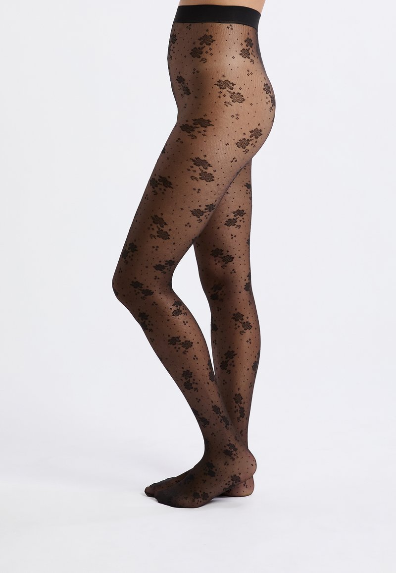 Tights negras con un patrón que presenta diseños florales y lunares. Hechas de un material transparente con una textura suave y una cinturilla ancha.
