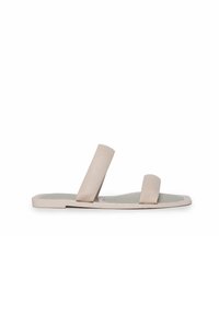 Sandalias planas beige con dos correas anchas, una textura suave y un diseño minimalista. La suela está ligeramente contorneada para mayor comodidad.