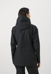 Schwarze wasserdichte Jacke mit einer passgenauen Kapuze, langen Ärmeln, strukturiertem Stoff und einem leicht taillierten Design. Verfügt über eine minimale Markenkennzeichnung auf der Rückseite.
