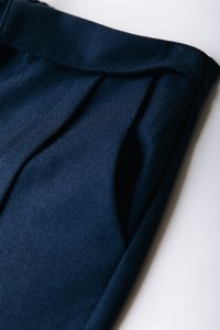 Ύφασμα σε ναυτικό μπλε με πιέτες και ραβδωτή υφή, εν μέρει διπλωμένο. Διαθέτει μονόχρωμο σχέδιο και λεία επιφάνεια. Κατάλληλο για χρήση σε ρούχα.