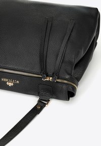 Borsa in pelle nera con texture a chicco di riso e zip e accessori in oro. Presenta due frange decorative e una tracolla rimovibile per una maggiore versatilità.