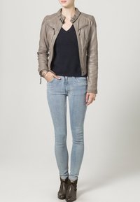 Lysebrun læderjakke med lynlåsslukninger, parret med en navy sweater og lyseblå skinny jeans. Brune ankelstøvler fuldender looket.