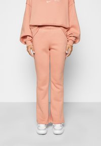 Sweatshirt cropped rosa claro e calças de fato flared a condizer, feitas de um tecido suave e macio, com um logotipo branco e detalhes de bolso.