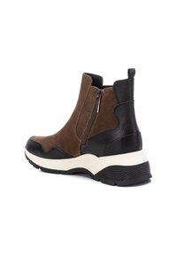 Botines de ante marrón con acentos texturizados en negro, con elástico en los laterales y cierre de cremallera. Suela media gruesa en crema y suela exterior de goma negra.