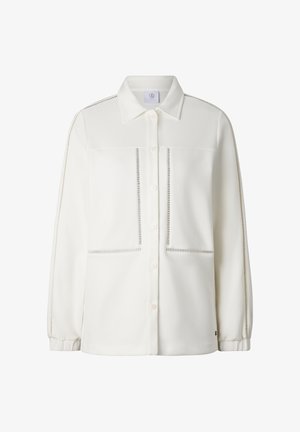 Witte blouse met lange mouwen, knoopsluiting, met geperforeerde rand langs de mouwen, zakken en voorkant, voorzien van een klassieke kraag en elastische manchetten.