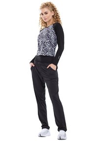 Black athletic joggers with a relaxed fit paired with a cropped, leopard print top featuring long black sleeves.