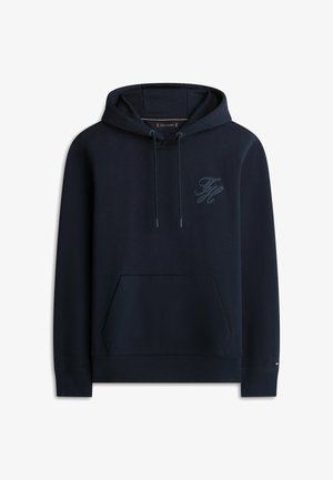 Granatowa bluza z kapturem z przednią kieszenią typu kangur, kapturem ze sznurkiem ściągającym oraz subtelnym logiem w tonacji wyszytym na lewej piersi.