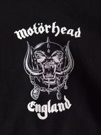 Tela negra con un gráfico detallado en blanco de un cráneo feroz con cuernos, cadenas y el texto "Motörhead Inglaterra" arriba y abajo.