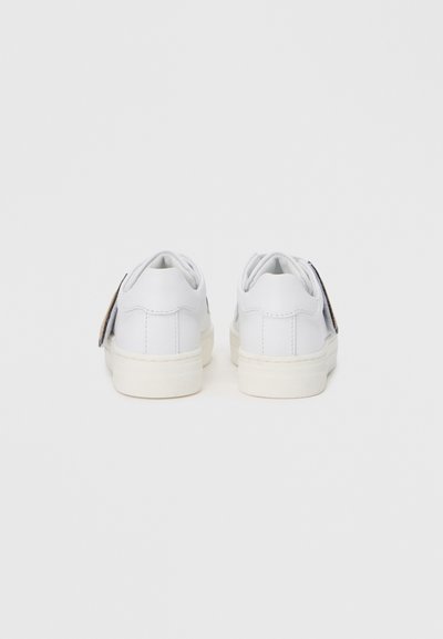 Λευκά αθλητικά παπούτσια χαμηλού τόνου με λείο δερμάτινο επάνω μέρος, αντιθετικές πλευρικές λεπτομέρειες, επενδεδυμένο περίγραμμα και λαστιχένια σόλα με ελάχιστη υφή.
