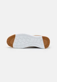 Flat sneaker sole features a white rubber base with textured grooves and a brown traction area at the toe. Clean, modern design.
