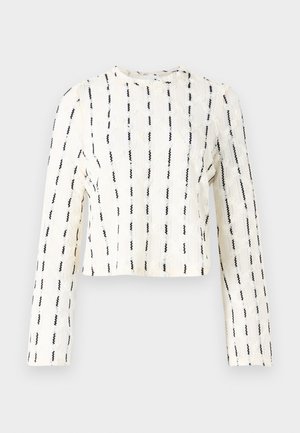 Afkortet langærmet top i cremet farve med sorte lodrette striber, tekstureret stof med subtile mønstre, rund halslinje og syede detaljer.