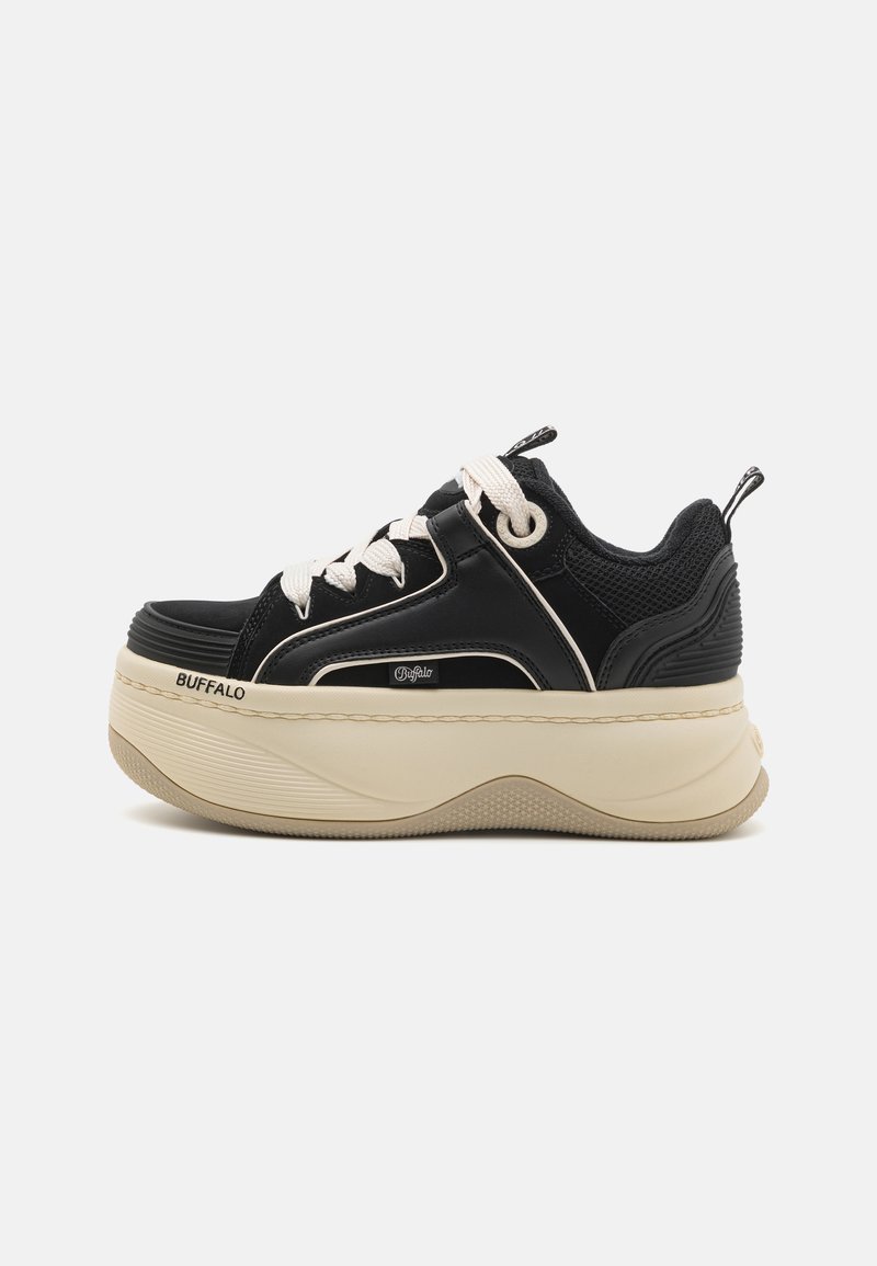 Sorte plattform sneakers med mesh- og syntetiske materialer. Rund tå, tykk kremfarget såle, hvite snører, og merkevarelogo på siden.