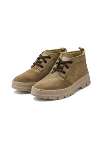 Botas de ante marrones hasta el tobillo con suela de goma beige, punta redonda y cordones marrones oscuros. Forro suave y lengüeta en la parte trasera para facilitar su uso.