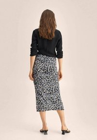 Musta kukkakuvioinen midi-hame, jossa on pieniä valkoisia ja laventelinvärisiä kukkia; sileä kangas; yhdistetty mustan neuleen kanssa; malli näkyy takaa.