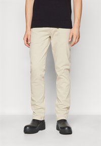 Beige bomullschinos med smal passform, med sidelommer och en jämn textur, parat med svarta sko med tjock sula.