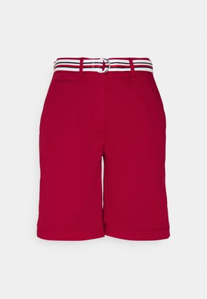 Pantalones cortos rojos hasta la rodilla con trabillas para cinturón y un cinturón de tela a rayas blancas, rojas y negras con hebilla de doble aro.