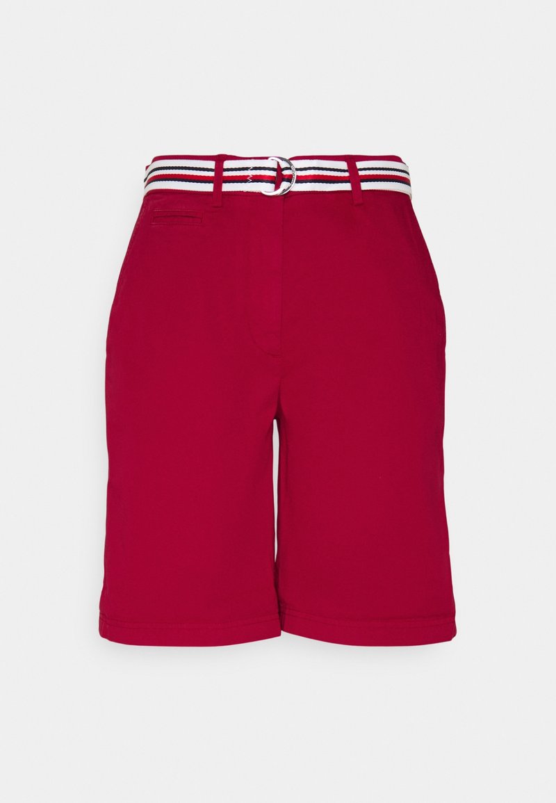 Shorts rouges longueur genou avec passants de ceinture et ceinture en tissu rayée blanche, rouge et noire avec boucle à double anneau.
