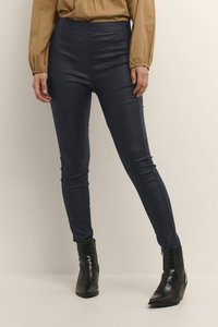 Marina faux läderleggings med en texturerad krokodilmönster, med slim fit och elastisk midja, i kombination med svarta ankelstövlar.