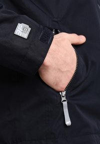 Námořnická bunda s kapsou na zip, suchým zipem na manžetách a logem. Texturovaná tkanina s elegantním designem a kontrastními zipy.