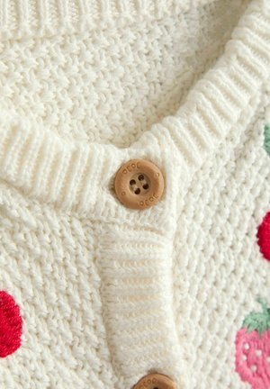 Krém színű kötött kardigán V-nyakkal, fa gombbal, piros epres hímzéssel és texturált felülettel.