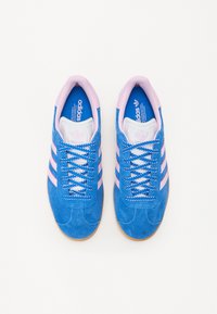 Sneaker in suede blu con accenti rosa e tre strisce. Presenta una fodera interna bianca, lacci blu e una suola in gomma.