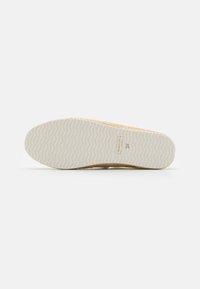 Semelle blanche de chaussure avec motif ondulé, nom de marque « GANT » et taille « 37 » embossés près de la zone du talon.