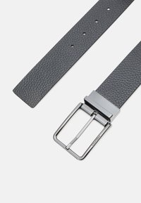 Cintura in pelle grigia con texture, dotata di una fibbia rettangolare in argento lucido e numerosi fori di regolazione per la flessibilità della taglia.