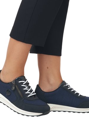 Navy blue athletic shoes with a mesh upper, white laces, and a zippered accent. Textured surface and contrasting white outsole, low-top design.