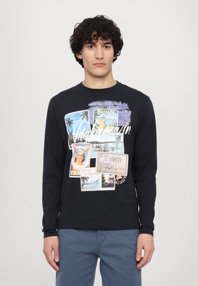 Camiseta de manga larga en color marino que presenta un collage de postales vintage, con varios colores e imágenes, sobre una suave tela de algodón.