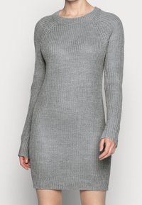 Robe grise tricotée avec un col rond côtelé, des manches longues et une silhouette ajustée. Tissu texturé avec un motif de tissage lâche.