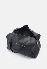 Mala de viagem de padrão preto com detalhes em dourado, apresentando alças superiores duplas e fecho de correr, destacando um interior espaçoso e textura suave.