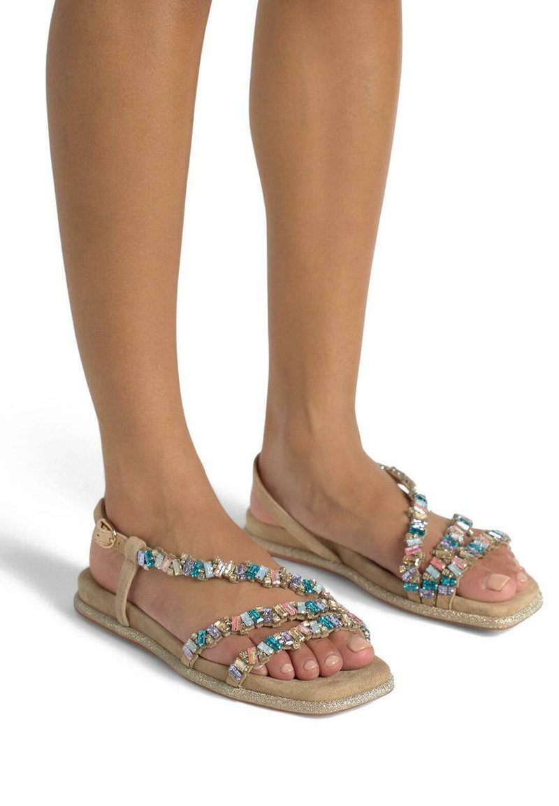 Sandali flat beige con gemme multicolori scintillanti sui cinturini, una morbida texture in camoscio e una suola leggermente glitterata.