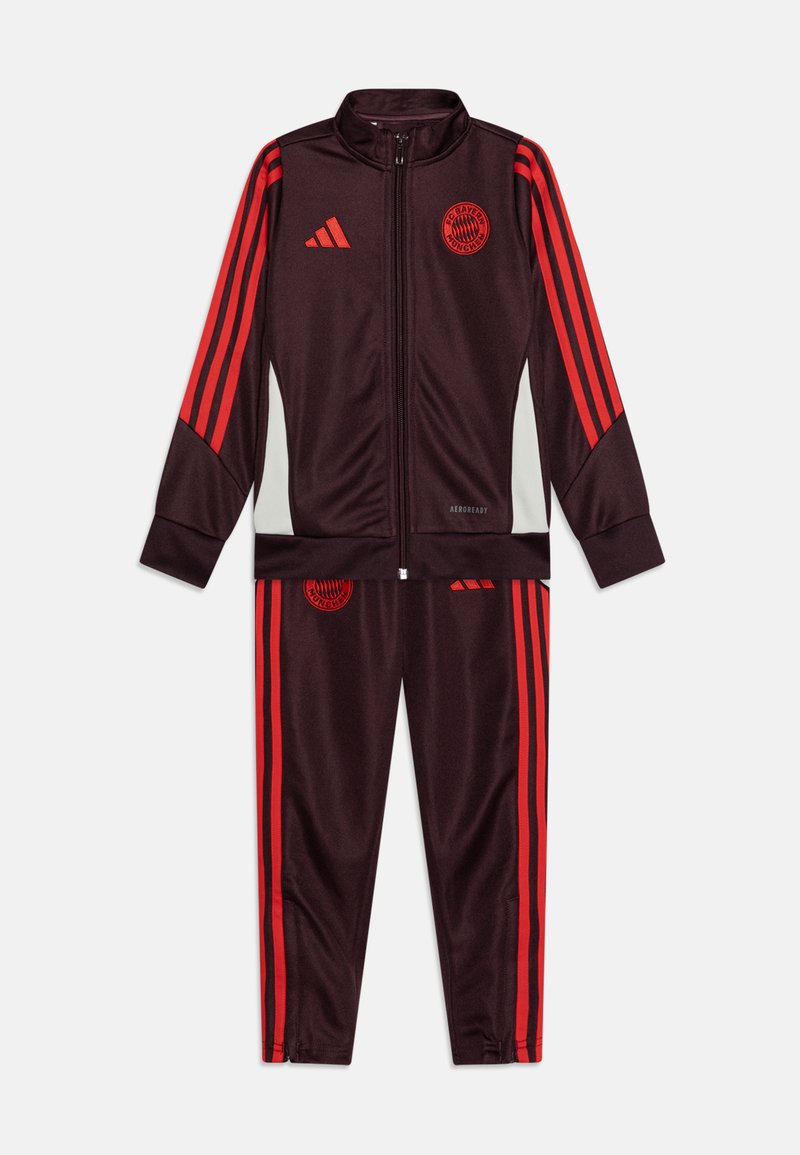 Tuta Adidas di un elegante bordeaux scuro con strisce rosse. Caratterizzata da una giacca con zip e pantaloni abbinati. Realizzata in tessuto liscio con un design sportivo.
