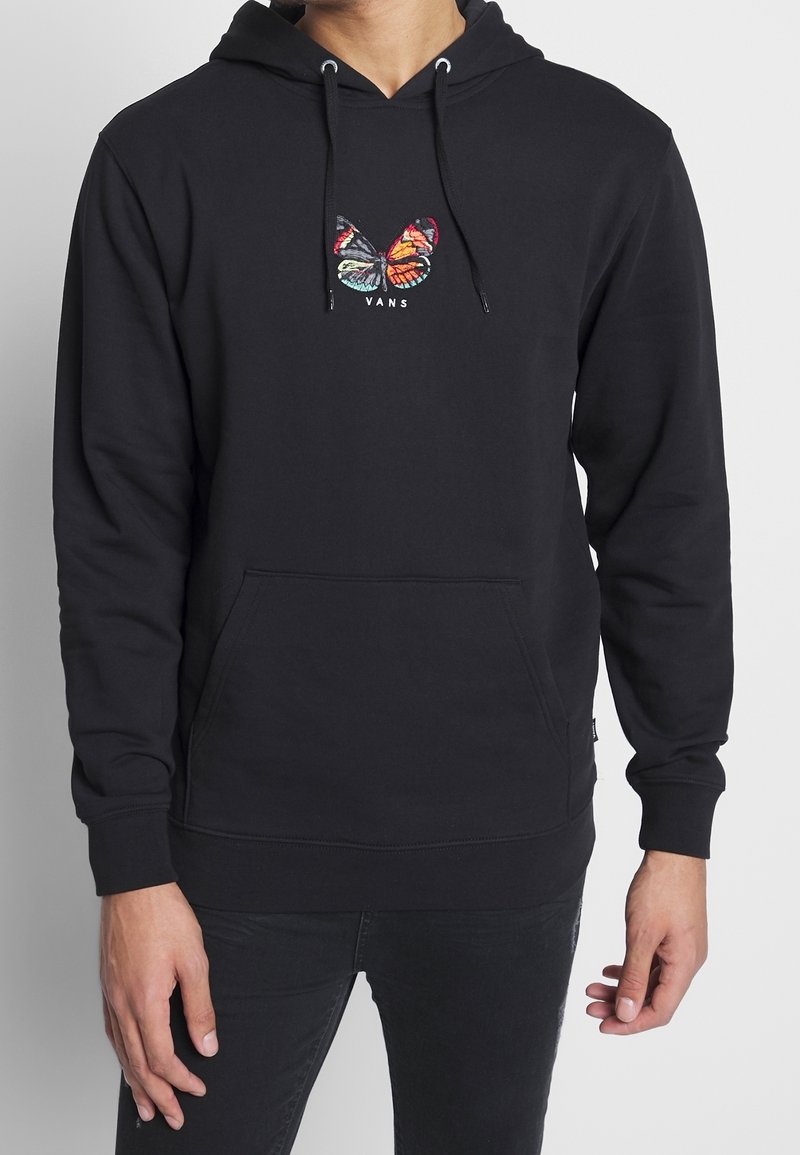 Felpa nera con tasca kangaroo frontale, caratterizzata da un design di farfalla ricamato in colori vivaci e testo "VANS" sottostante.