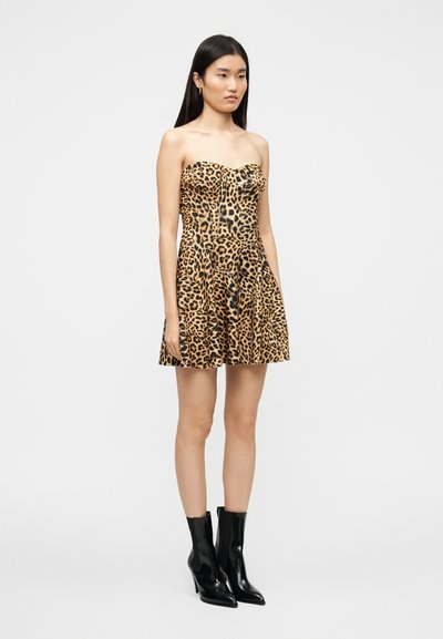 Φόρεμα χωρίς τιράντες με λεοπάρ σχέδιο και φούστα που ανοίγει, κατασκευασμένο από λείο ύφασμα. Συνδυάζεται με μαύρα, γυαλιστερά μποτάκια αστραγάλου.
