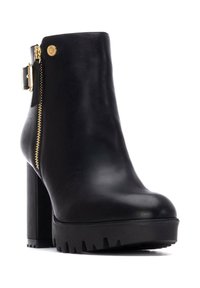 Stivale alla caviglia in pelle nera con tacco alto e spesso, zip laterale, finiture dorate e suola in gomma testurizzata. Finitura liscia con un design elegante.