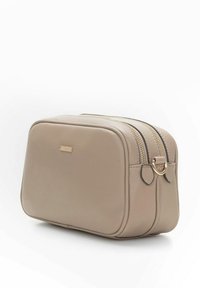 Beżowa, prostokątna skórzana kosmetyczka z dwoma zapinanymi na zamek kieszeniami i małą złotą plakietką z logo na przedzie.
