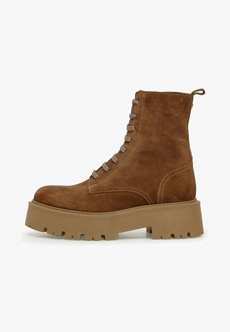 Rudas suede aulių batai su apvalia nosimi, pilkomis raištelėmis ir storo, tekstūruoto smėlio spalvos padu. Savybė - dekoratyviniai siūlai palei šoną.