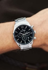 Silver metal watch with a black dial, three sub-dials, silver hour markers, and a date display. Stainless steel bracelet with a polished finish.