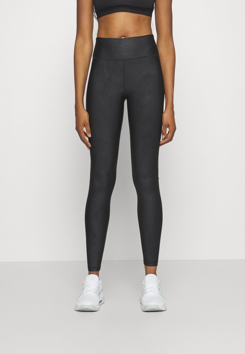 Black athletic leggings with a textured diamond pattern, high waist, and fitted design, paired with white athletic sneakers.