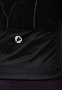 Μαύρο ένδυμα από υφασμάτινη υφή με ραμμένα ράμματα και μικρό λευκό κυκλικό λογότυπο με μαύρο σκορπιό.