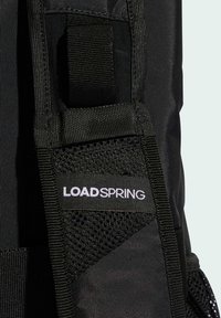 Svart ryggsäck med texturerat tyg, meshdetaljer och en framträdande vit "LOADSPRING"-logotyp. Justerbar rem ingår.