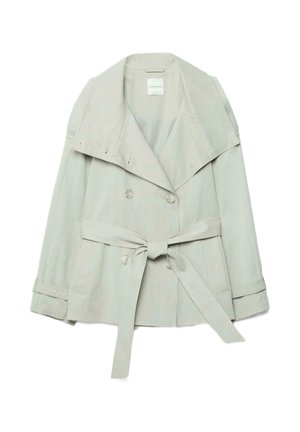 Lyse beige dobbeltradet trenchcoat med brede revers, taljebælte bundet foran og knappede manchetter, lagt fladt på hvid baggrund.