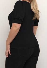 Black short-sleeve top with puffed sleeves and a fitted design. Made of a smooth fabric, featuring a round neckline and a slightly curved hem.