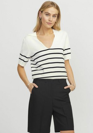 Top blanco de manga corta con rayas horizontales negras y cuello en V, combinado con pantalones cortos negros a medida. Textura suave.