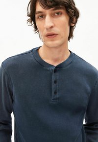 Marineblaues, geripptes Henley-Shirt mit langen Ärmeln, rundem Ausschnitt, dreiknöpfiger Blende und strukturierter Stoff.