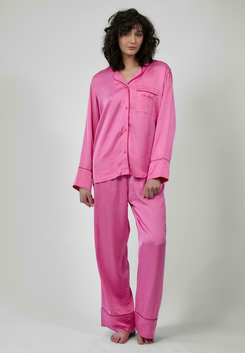 Set di pigiami in satin rosa composto da una camicia a maniche lunghe con bottoni e tasca e pantaloni abbinati. Tessuto morbido e vestibilità comoda.